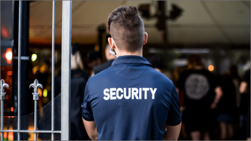Security officer in a navy polo monitoring a venue gate