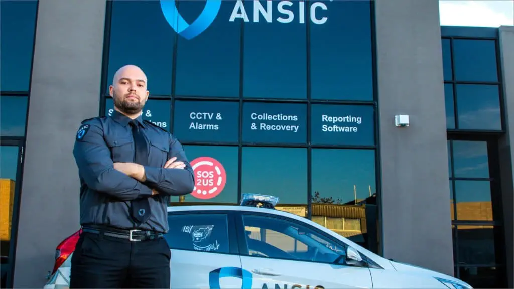 ANSIC officer beside a marked ANSIC patrol vehicle